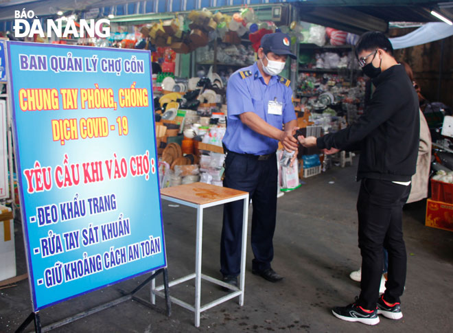 Visitors to the Da Nang-based Con Market are seen having their body temperatures measured and washing their hands with the use of sanitizer gel before their entry