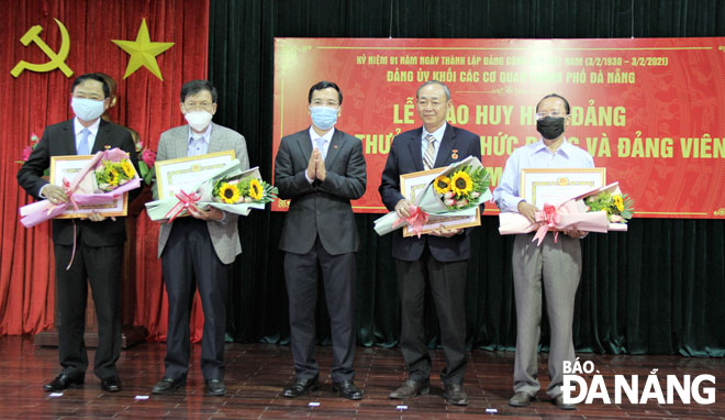Bí thư Đảng ủy khối Các cơ quan thành phố Nguyễn Hữu Lợi (giữa) trao Huy hiệu Đảng cho các đảng viên đủ tiêu chuẩn. Ảnh: L.P