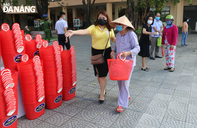 Staff of the organising board assisting an elderly woman to do shopping at the charity market