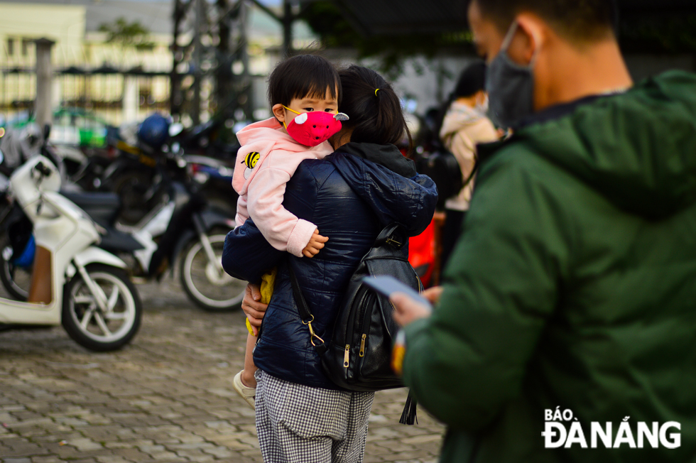 A little girl preparing to get on a coach with her parents to return home in celebration of Tet