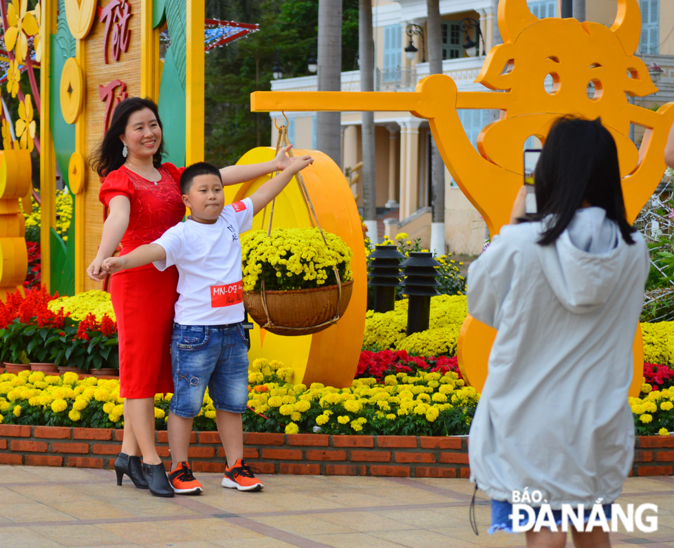 A young boy with his mother taking a photo at the Bach Dang colourful flower street