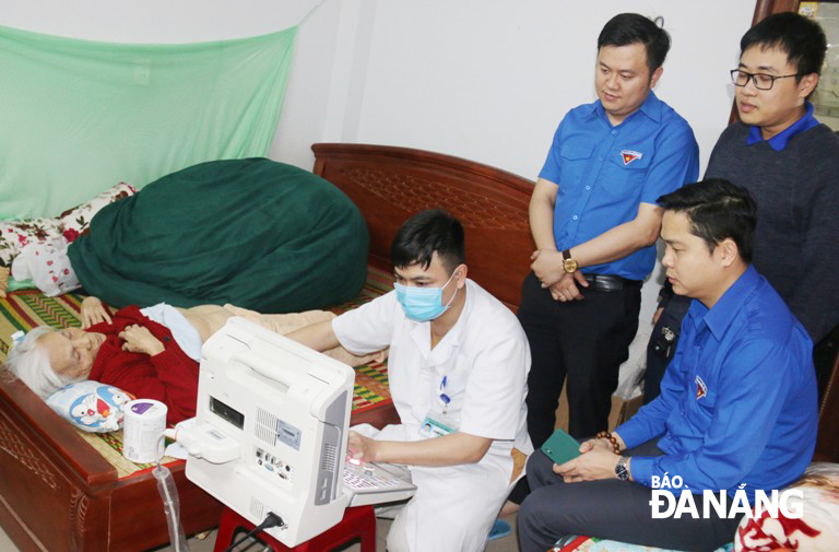 Young medical workers from the Da Nang General Hospital are seen giving free medical checkups to heroic Vietnamese mother Phan Thi Trinh at home