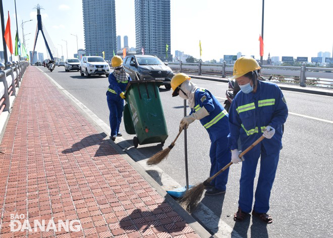 Các công nhân của Công ty CP Môi trường Đô thị Đà Nẵng đang tập trung vệ sinh môi trường trong ngày 11-2, bảo đảm đường phố sạch, đẹp đón Tết. Ảnh: HOÀNG HIỆP