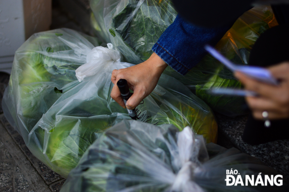 A volunteer marking bags of cabbages carefully before delivering them to buyers across the city