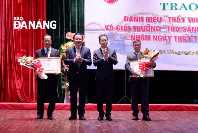 Da Nang Party Committee Secretary Nguyen Van Quang (2nd from right) hands over Certificates of Merit from the Prime Minister and municipal People's Council Vice Chairman Le Minh Trung (2nd from left) presents congratulatory bouquets to two individuals on Friday morning for recognition for their outstanding contributions to the local healthcare sector.