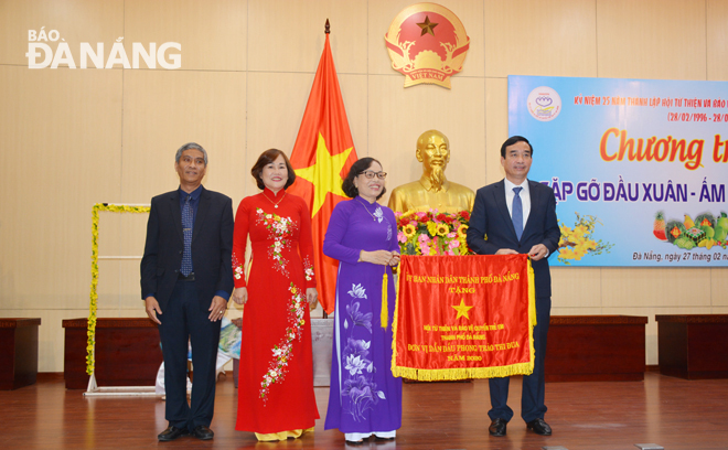 Đồng chí Lê Trung Chinh tặng cờ Đơn vị dẫn đầu phong trào thi đua năm 2020 của UBND thành phố cho Hội Từ thiện và Bảo vệ quyền trẻ em thành phố. Ảnh: LÊ VĂN THƠM