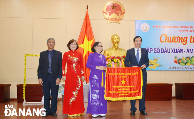 Chủ tịch UBND thành phố Lê Trung Chinh (bìa phải) tặng cờ Đơn vị dẫn đầu phong trào thi đua năm 2020 của UBND thành phố cho Hội Từ thiện và Bảo vệ quyền trẻ em thành phố. Ảnh: LÊ VĂN THƠM	