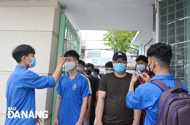 Students are seen queuing in 2 rows to have their body temperature measured and use hand sanitizer gel at the entrance gate to the Da Nang University of Science and Education on Monday morning.