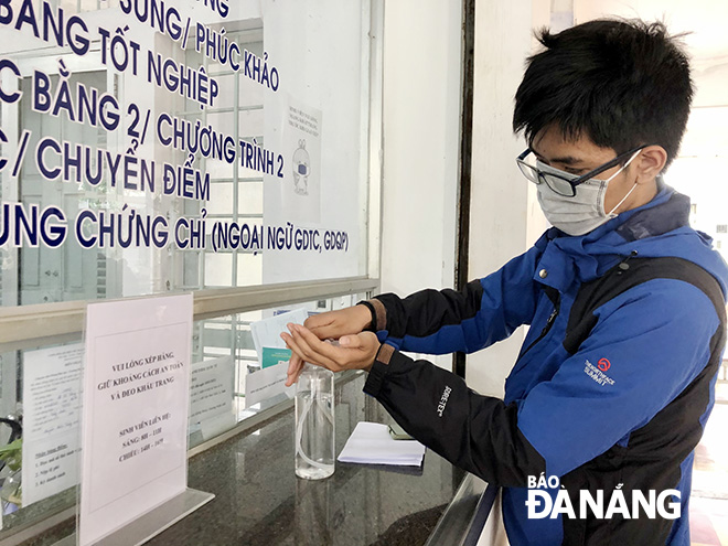 Students of the Da Nang University of Science and Technology disinfect their hands before entering lecture halls.