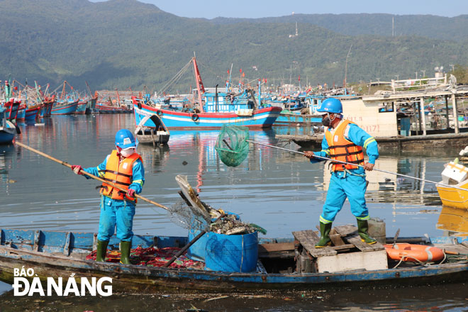 URENCO workers scavenging trash floating in a river at the Tho Quang fishing wharf 	