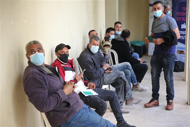 Người lao động Palestine chờ tiêm vaccine ngừa Covid-19 gần thành phố Tulkarem, Bờ Tây ngày 8-3-2021. Ảnh: THX/TTXVN