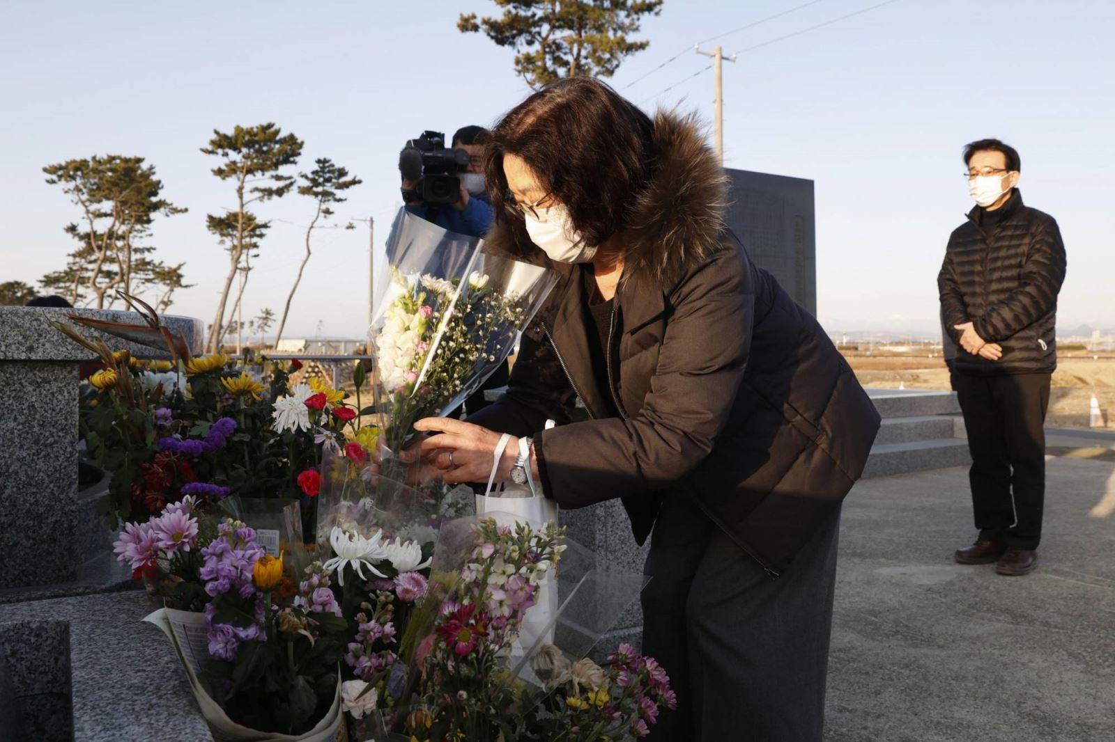 Một người phụ nữ dâng hoa tại một đài tưởng niệm ở Sendai vào ngày 11-3. Ảnh: Kyodo