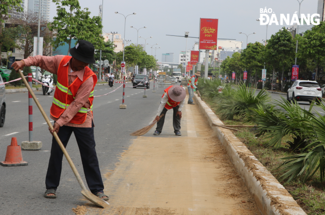 Construction workers cleaning up work areas to ensure the safety of road users