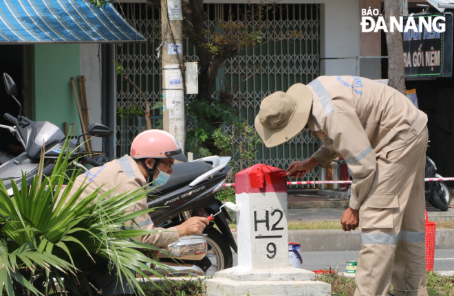 Some construction workers repainting a H pile on a median strip 