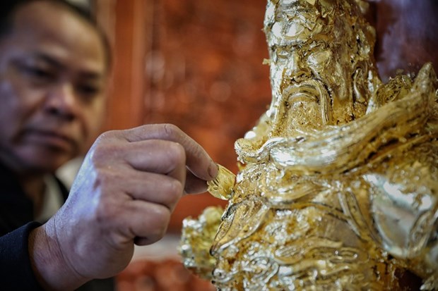 An artisan in Kieu Ky village overlays a statue with super-thin gold leaves (Photo: VNA)