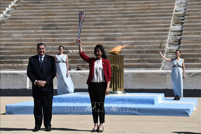 Bộ trưởng Thể thao Hy Lạp Spyros Capralos (trái) trao ngọn đuốc Olympic cho cựu vận động viên bơi lội Nhật Bản Imoto Naoko tại Athens, Hy Lạp, ngày 19-3-2020. Ảnh: AFP/ TTXVN