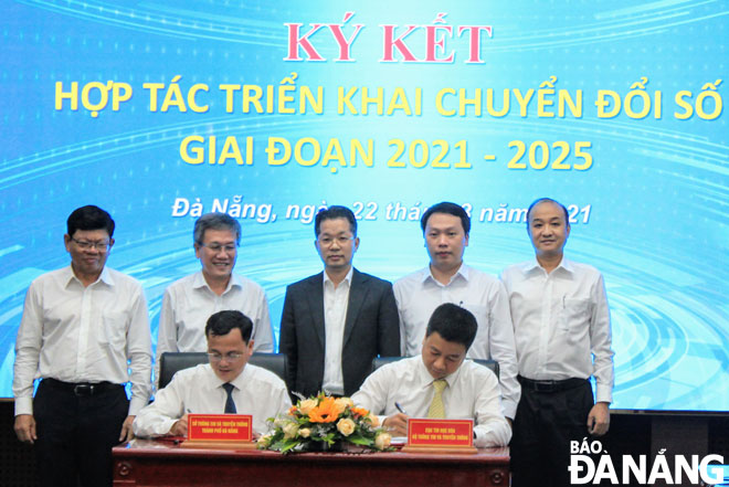 Da Nang Party Secretary Quang (centre) witnessing the signing of a Memorandum of Understanding on digital transformation between the municipal Department of Information and Communications and the Department of Information Technology under the Ministry of Information and Communications
