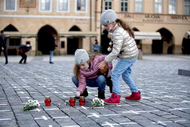 Trẻ em đặt nến và hoa tưởng niệm các bệnh nhân tử vong do Covid-19, tại quảng trường Old Town ở Praha, CH Séc, ngày 22/3/2021. Ảnh: THX/ TTXVN