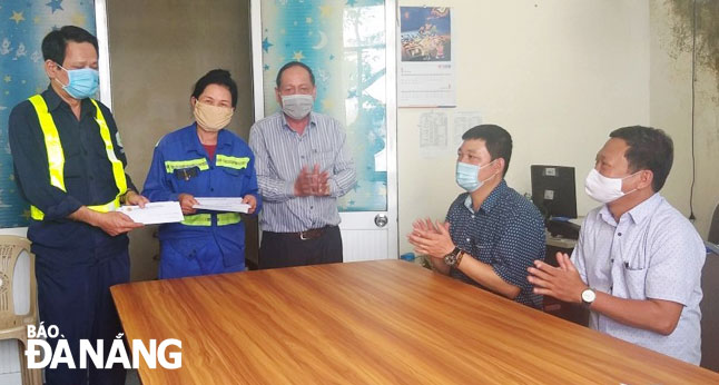 A representative from the Da Nang Urban Environment JSC (right) rewarding the two sanitation workers for having returned properties to their owners