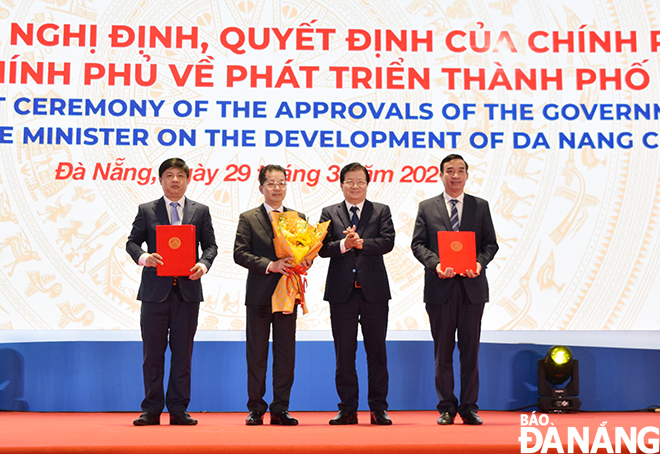 Phó Thủ tướng Chính phủ Trịnh Đình Dũng trao các nghị định, nghị quyết của Chính phủ, Thủ tướng Chính phủ đến lãnh đạo thành phố Đà Nẵng . Ảnh: TRIỆU TÙNG