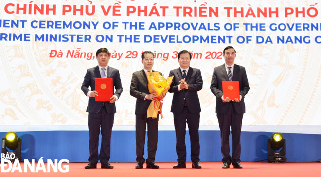 Phó Thủ tướng Trịnh Đình Dũng (thứ 2, phải sang) trao các nghị quyết, quyết định của Chính phủ, Thủ tướng Chính phủ đến lãnh đạo thành phố Đà Nẵng. Ảnh: TRIỆU TÙNG	