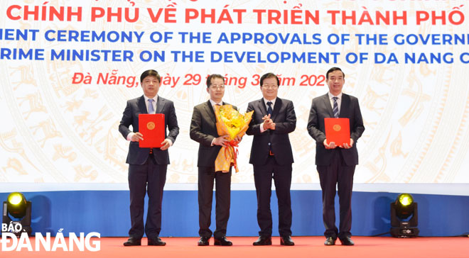 Deputy Prime Minister Trinh Dinh Dung (2nd, right) handing over the resolutions and decisions apprved by the national government and the Prime Minister to the Da Nang leaders