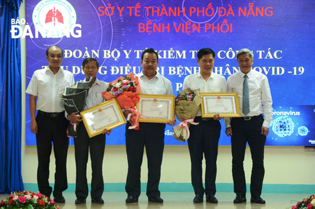Thứ trưởng Bộ Y tế Nguyễn Trường Sơn (bìa phải) và Phó Chủ tịch UBND thành phố Lê Quang Nam (bìa trái) trao bằng khen của Bộ Y tế và tặng hoa cho 3 cá nhân có thành tích trong công tác phòng, chống Covid-19. Ảnh: PHAN CHUNG