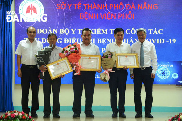 Deputy Minister of Health Nguyen Truong Son (right) and Da Nang  Peoples Committee Vice Chairman Le Quang Nam (left) awarding certificates of merit from the Ministry of Health to three individuals in recognition of their remarkable achievements in COVID-19 prevention and control.