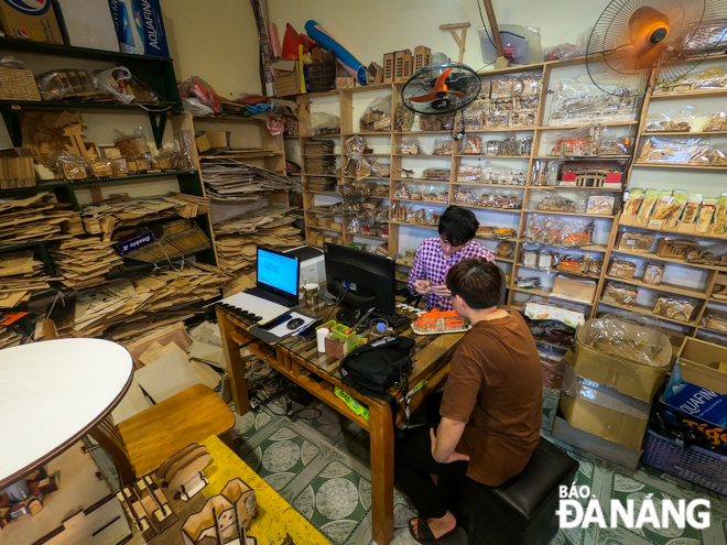 Nguyen Van Binh (in striped shirt) is keen on making designs for his wooden products in his workspace Binh operates the laser engraving machine