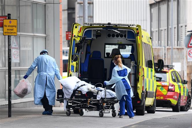 Nhân viên y tế chuyển bệnh nhân Covid-19 tới bệnh viện ở London, Anh. Ảnh: AFP/TTXVN