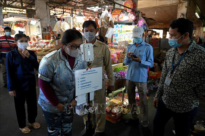  Kiểm tra thân nhiệt phòng lây nhiễm Covid-19 tại một khu chợ ở Phnom Penh, Cambodia, ngày 17-3-2021. Ảnh: AFP/TTXVN