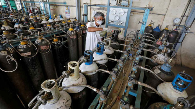Một công nhân khử trùng vòi phun bình oxy tại một nhà máy ở thành phố Ahmedabad, bang Gujarat của Ấn Độ ngày 25-4. Ảnh: Reuters	