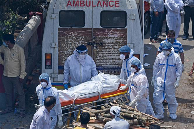 Nhân viên y tế chuyển thi thể bệnh nhân Covid-19 tới khu hỏa táng ở New Delhi, Ấn Độ ngày 27-4-2021. Ảnh: AFP/TTXVN