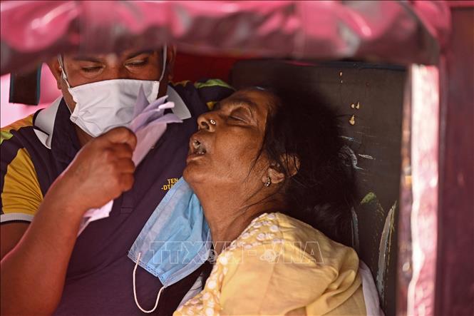 Một bệnh nhân COVID-19 chờ được hỗ trợ thở oxy tại một lán trại dựng ven đường ở Ghaziabad, Ấn Độ ngày 26/4/2021. Ảnh: AFP/TTXVN