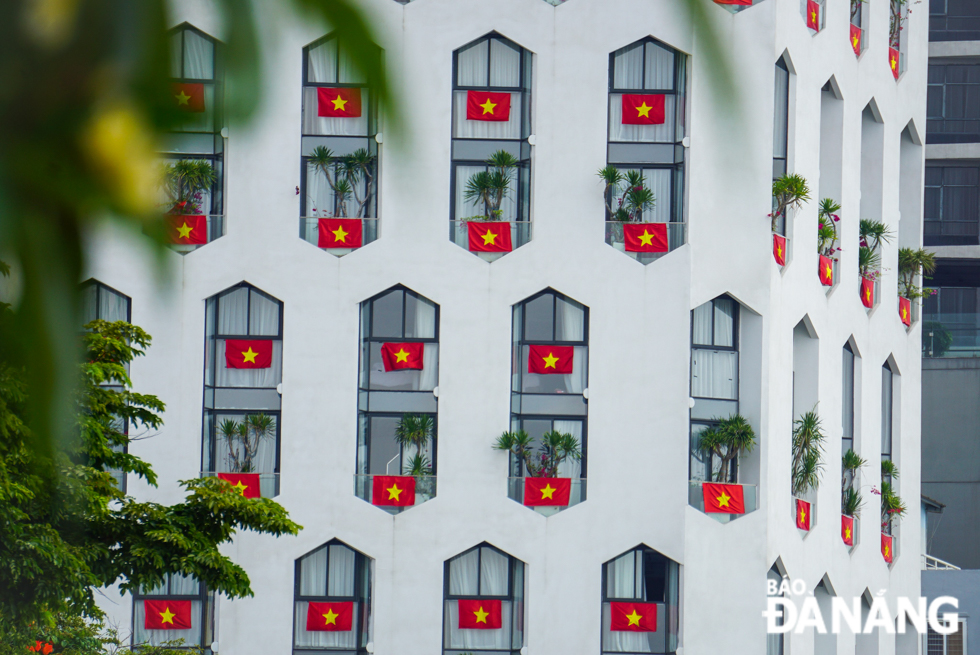 The windows of a hotel located on Bach Dang Street are adorned with national flags.