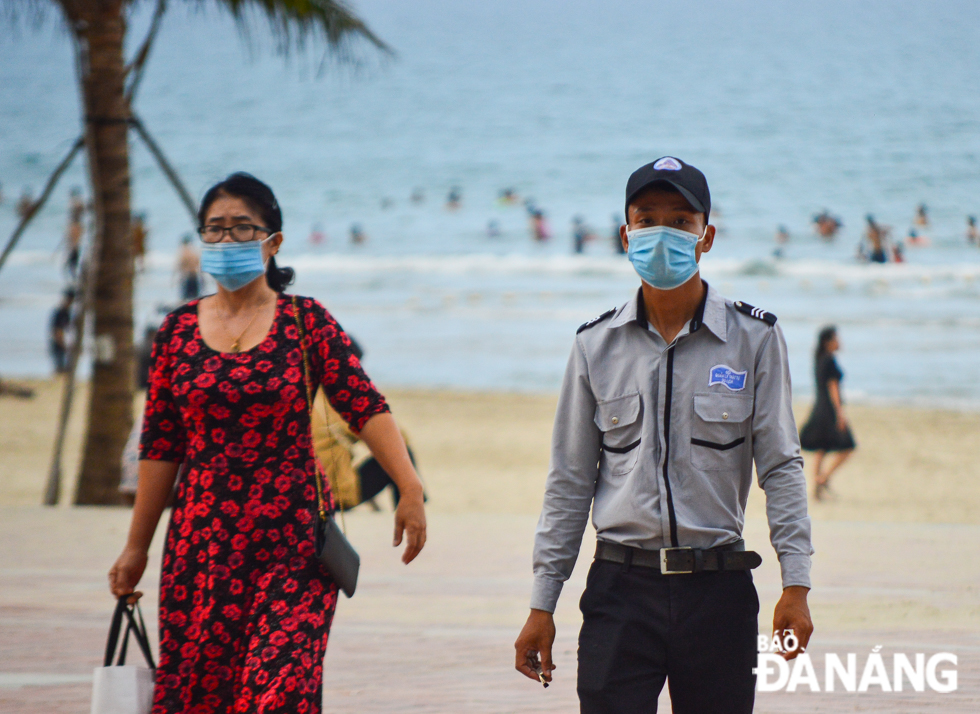 Mr Tran Phuc Yen, an employee of the beach tourism security protection force (right) said, “On this peak occasion, the number of tourists coming to Da Nang is quite large. We are on hand to remind visitors of wearing face masks on beaches”.