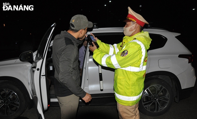 Traffic police officers perform breath tests for alcohol on drivers.
