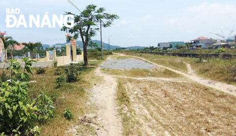 Một đoạn đường đất ven sông thuộc khu tái định cư Hòa Liên 4, huyện Hòa Vang, chưa được thảm nhựa. Ảnh: ĐẮC MẠNH	