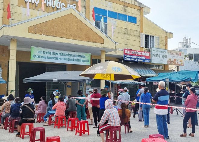 People are seen wearing face coverings and keeping a safe distance from others while in line to get coronavirus tests.