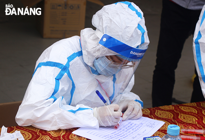 A female medical worker checking personal information of people who get a coronavirus test after taking their swabs.