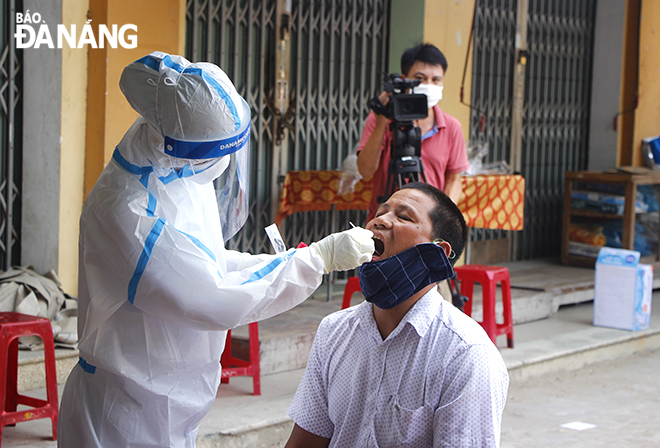 A medical worker collecting a throat and nose swab from a stall holder