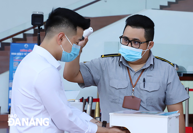 Visitors to the Da Nang Administrative Centre are seen having their body temperatures measured and disinfecting their hands before their entry. Photo: NGOC PHU