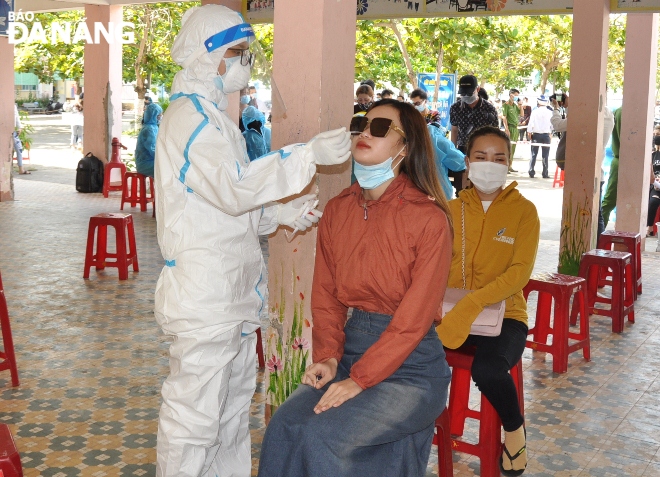 A medical worker collects a nose swab from a woman working in a service facility in Son Tra District. Photo: L.HUNG