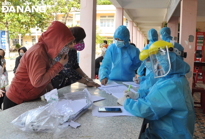 Medical staff re-check personal information of the employees before sample taking. Photo: L.HUNG