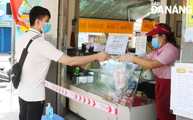 Nhiều cửa hàng, cơ sở kinh doanh dịch vụ ăn uống nghiêm túc thực hiện việc bán hàng mang về. Trong ảnh: Một tiệm bánh mì trên đường Nguyễn Chí Thanh yêu cầu khách hàng giữ khoảng cách khi mua hàng (ảnh chụp trưa 7-5). Ảnh: VĂN HOÀNG