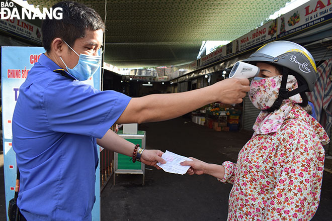 Patrons are required to present their entry cards, disinfect their hands and wear a face mask before entering the market. They are only allowed entry on their permitted dates. Picture was taken at the Dong Da Market on Sunday morning. Photo: KHANH HOA