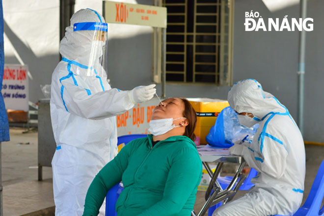 Cán bộ y tế lấy mẫu xét nghiệm SARS-CoV-2 cho tiểu thương chợ Hòa Khánh Nam, quận Liên Chiểu vào chiều 9-5. Ảnh: XUÂN SƠN	