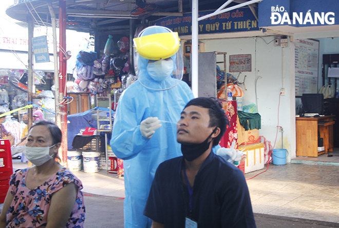 A stall holder in the Con traditional market has his nose swab samples collected for SARS-CoV-2 testing on May 13.