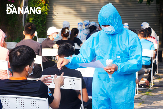 Nhân viên y tế quận Sơn Trà phát mẫu xét nghiệm cho người lao động các công ty tại Khu công nghiệp Đà Nẵng. Ảnh: XUÂN DŨNG