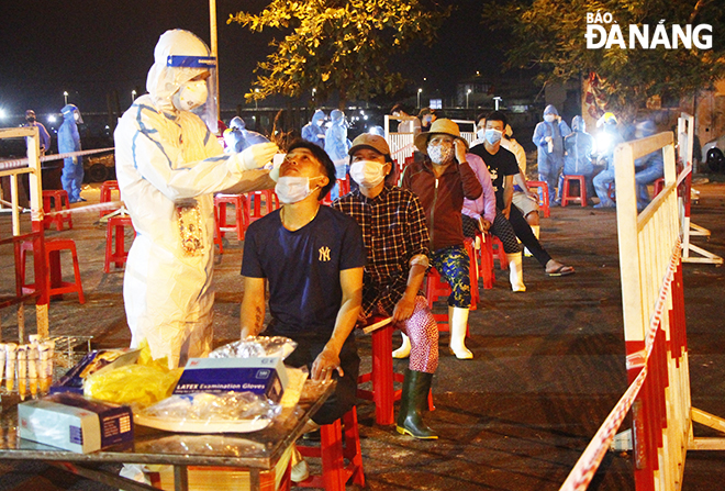 Staff of the Son Tra District Medical Centre conducted overnight collection of swab samples for COVID-19 testing from people in the Tho Quang fishing wharf and seafood wholesale market. Photo: XUAN DUNG